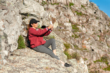 young woman above the mountains in the middle of nature taking photos of the landscape and likewise...