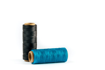 A skein of black and cyan thread. Coils of colored threads on a white background. Waxed sewing thread for leather goods.