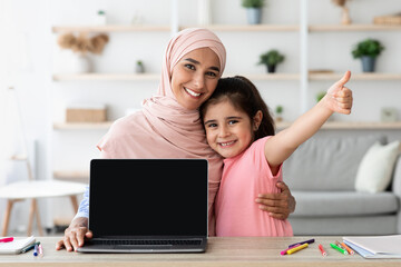 Website Ad. Muslim Mother And Little Daughter Demonstrating Laptop With Black Screen