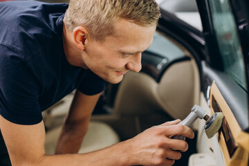 Man at car service polishing car details