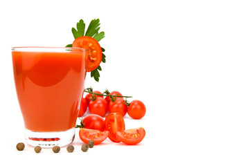 A glass of tomato juice with a tomato slice on the edge. Tomatoes, parsley and allspice are spread...