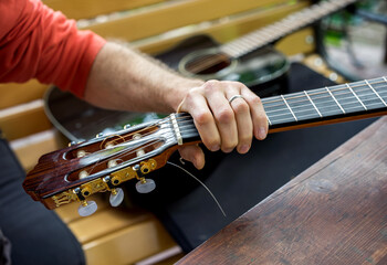 Man takes a classical acoustic guitar in the hand, lying on the wooden table - Powered by Adobe
