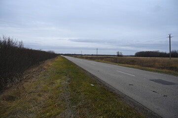 Autumn cloudy day. Russian steppes. Asphalt road stretching beyond the horizon.