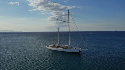 Fototapeta premium Aerial photo of luxury yacht - sail boat anchored in deep blue waters of Santorini island, Cyclades, Aegean, Greece