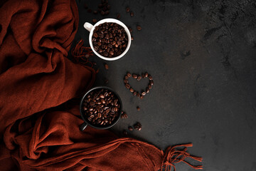 Fototapeta na wymiar Coffee beans in a cup on a dark background. Autumn, coffee composition. Maple leaves, brown scarf. Flat lay.
