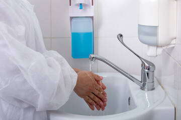 Tdoctor washes his hands with antiseptic in white sink. concept is the necessary hygiene measures...