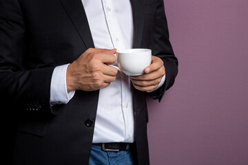 man in a black jacket holds a white mug of tea in his hands. Free space on the mug for inscription....
