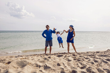family of three in blue clothes back on a sandy beach the sea in summer on vacation