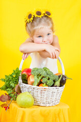 Beautiful little happy girl with basket vegetables and fruits