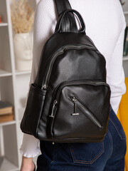 black backpack bag with straps on girl's back. bag for things, accessories and textbooks. Leather backpack with locks.