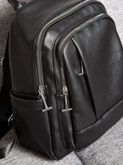 Black backpack bag with straps with zippers. bag for things, accessories and textbooks is in interior of apartment.