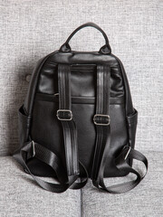Black backpack bag with straps with zippers. bag for things, accessories and textbooks is in interior of apartment.