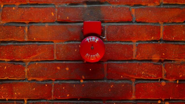 Smoke alarm on a wall. The red alarm bell is ringing while the fire spreading.