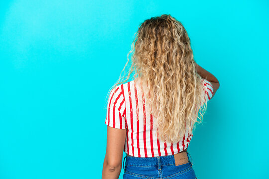 Girl with curly hair isolated on blue background in back position and thinking