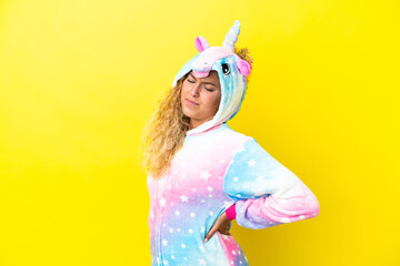 Girl with curly hair wearing a unicorn pajama isolated on yellow background suffering from backache for having made an effort