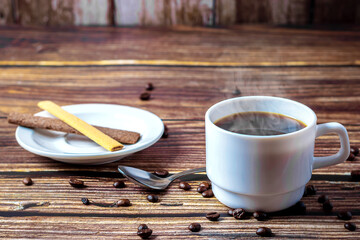 On a wooden table, a cup of hot aromatic coffee and scattered coffee beans. An invigorating morning...