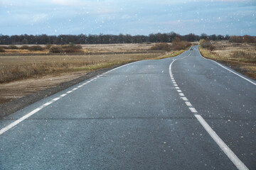 дорога по которой едет машина, пасмурно, идет первый снег
the road on which the car is driving is cloudy, the first snow is falling