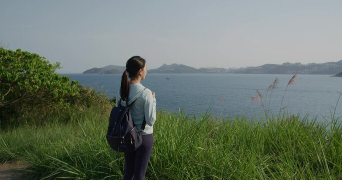 Woman go hiking and stand at the mountain and look at the sea
