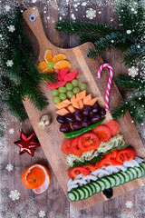Fototapeta na wymiar close-up of elegant Christmas tree made of vegetables and fruits, beautiful green pine branches, bright red decorations, sweet candies, concept of a Christmas holiday