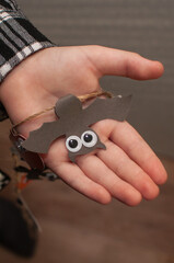 a bat with paper eyes for Halloween in the child's hand in vertical format
