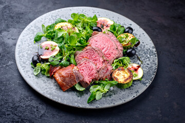 Modern style traditional fried dry aged angus beef filet medaillons with vegetable and lambs lettuce served on a Nordic design plate