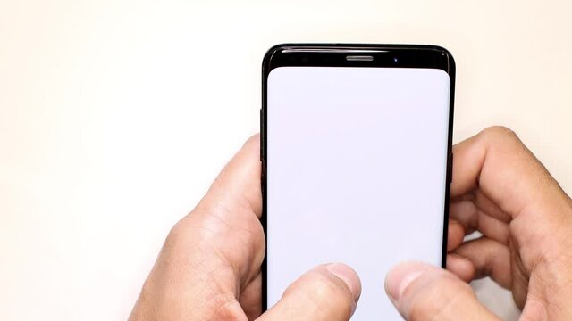 Holding telephone blank minimal template. Man scrolling on smartphone screen with white background. Smartphone template with gesture and scrolling action.