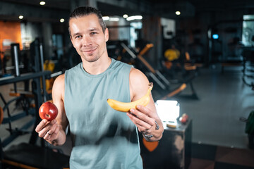 young handsome athlete hungry and eating healthy apple fruit in gym