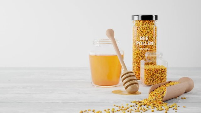 A jar of honey, dipper, wooden scoop and glass pots full of bee pollen granules