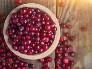 Ripe fresh cranberries in a wooden bowl on a rustic table top.
