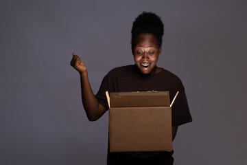 excited young black woman opening a box