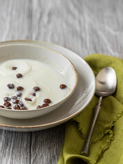 Dry breakfast. Milk splashing into a bowl with chocolate cornballs. A bowl of chocolate flakes on the table.