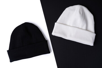 Two stylish fashion beanie hats in basic colors black and white on a black and white background. Top view