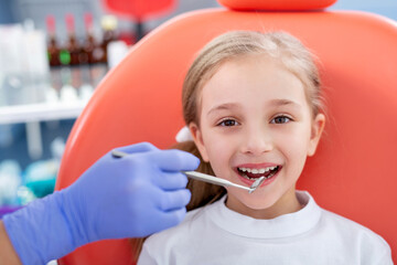 child girl in white clothes at reception at a pediatric dentist smiles and laughs. little girl checks caries with a children's doctor concept is children's health.
