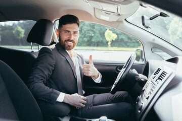 Businessman shows thumbs up and looks at the camera with a smile urges to pinch and use the seat belt in the car