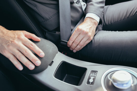 A man in a business suit fastens a car seat belt photo close up