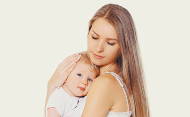 Portrait of beautiful young mother hugging and soothes her baby on a white background