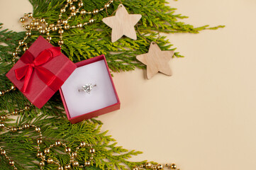 a white gold ring with a large gemstone in a red gift box with a bow on the background of a green...