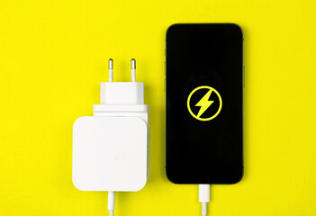 Lightning charger adapter for smartphone. Charge the mobile device. Yellow background, flat lay,...