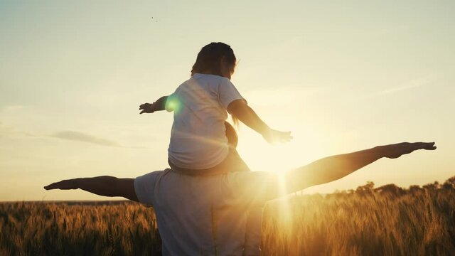 dream future concept. kid girl daughter sits on father neck play in superhero aviator pilot. silhouette at sunset. happy family people in the park. parent dad and a small lifestyle child playing