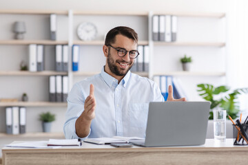 Obraz premium Happy mature caucasian guy with beard in glasses work at laptop, making video call and gesturing