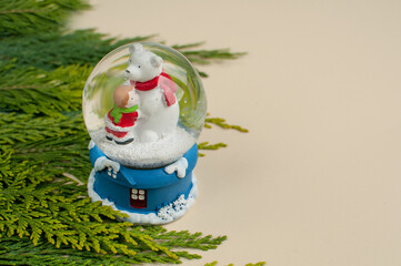 A snow ball toy with a white Christmas bear and a baby on a blue stand on a beige background with...