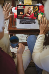 Two men making christmas laptop video call waving to smiling caucasian woman