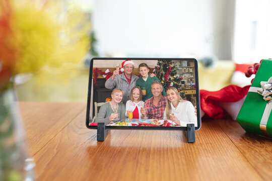 Happy Caucasian Multi Generation Family At Christmas Smiling On Tablet Video Call Interface Screen