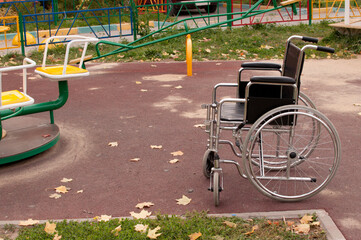 an empty wheelchair is standing on the street on the asphalt on the children's playground in the...