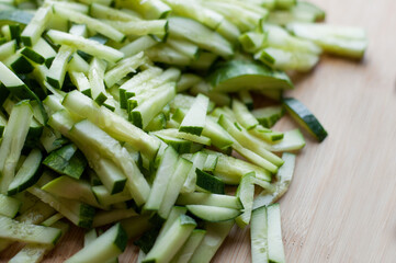 Finely sliced fresh cucumbers on a wooden cutting board with blurred edges