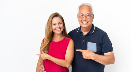 Middle age couple isolated on white background pointing finger to the side and presenting a product