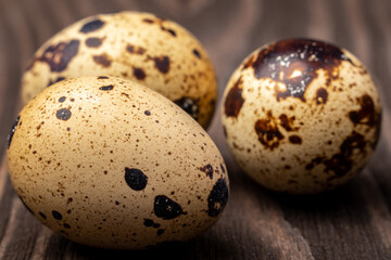three quail eggs on a wooden background closeup