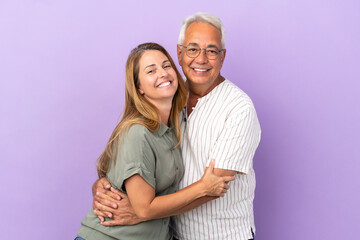Middle age couple isolated on purple background hugging
