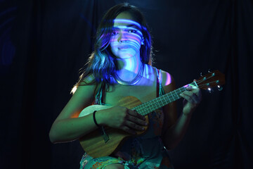 Fototapeta premium A woman in a black dress is learning to play the ukulele with visual effects
