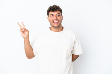 Fototapeta premium Young caucasian handsome man isolated on white background smiling and showing victory sign